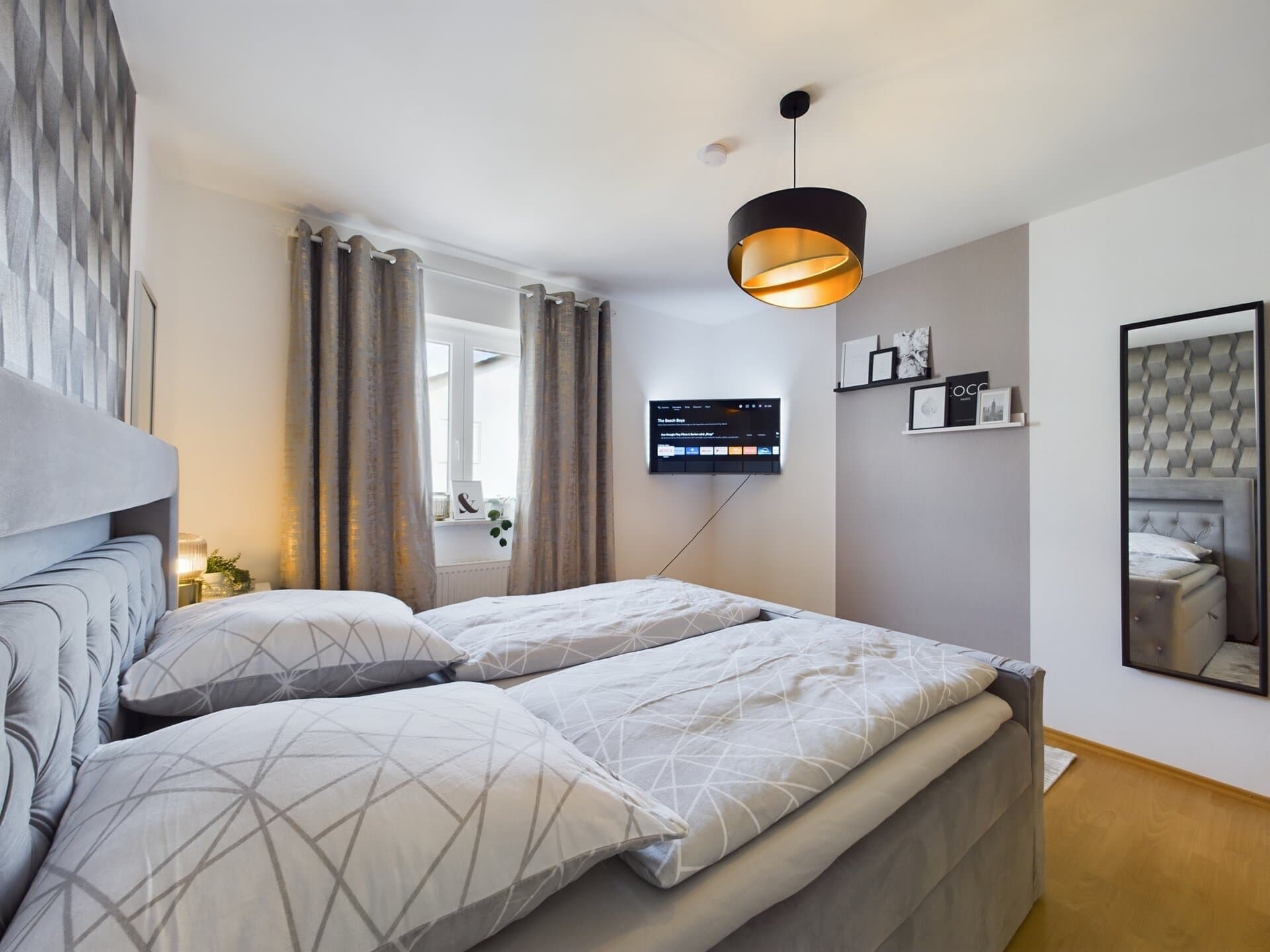 Modern bedroom with large bed, wall-mounted TV, and stylish decor near Ramstein Air Base.
