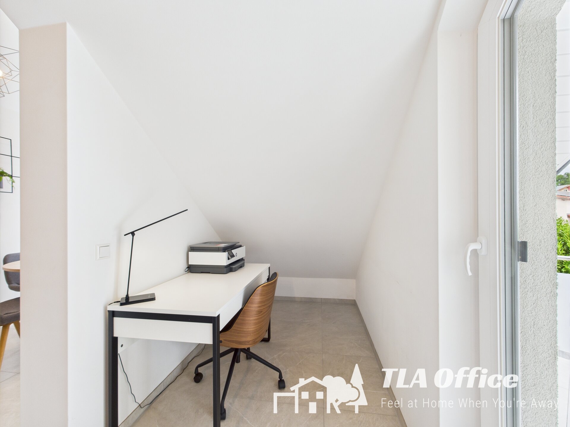 Modern white home office corner with desk and chair near window.