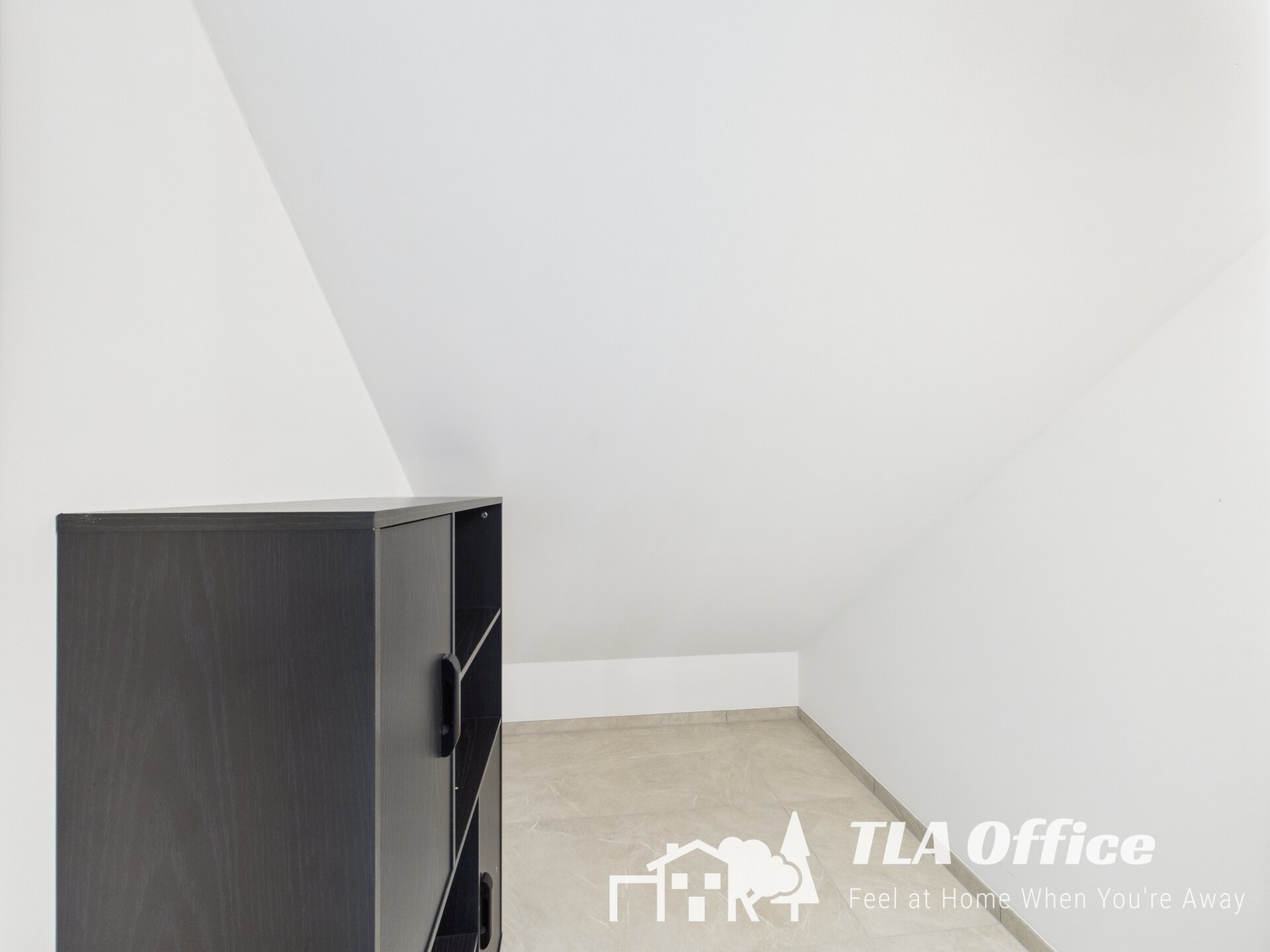 Modern black storage cabinet in a bright, white room with sloped ceiling.